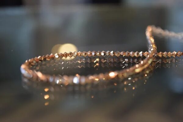 A 13-18" Rose Gold x2 Necklace/Choker with gold beads on top of a glass table.