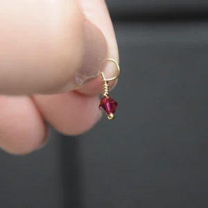 A person holding a January Birthstone 4mm Dangle on a gold chain.