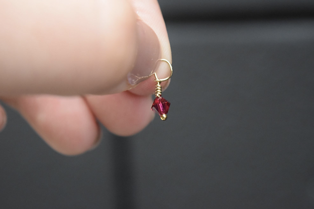 A person holding a January Birthstone 4mm Dangle on a gold chain.