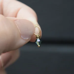 A person's hand holding a small April Birthstone 4mm Dangle.