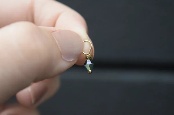 A person's hand holding a small April Birthstone 4mm Dangle.