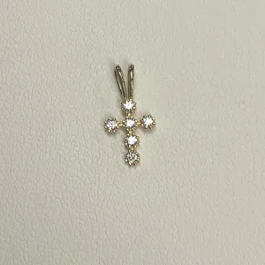 A 14K Yellow gold bezel set CZ cross pendant with diamonds on it.