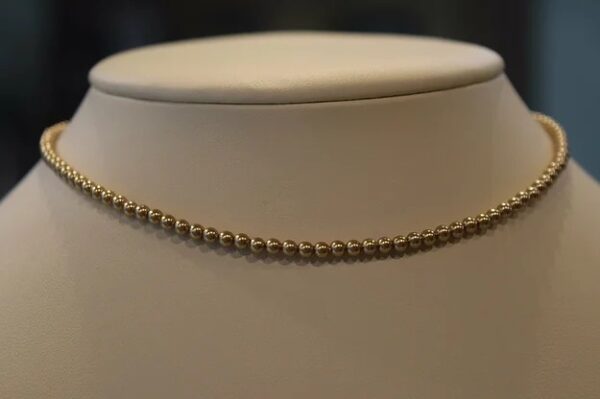 A 13-18" Bright Gold Pearl Choker/Necklace on a mannequin mannequin.