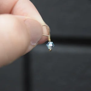 A person holding a March Birthstone 4mm Dangle dangling from a gold earring.