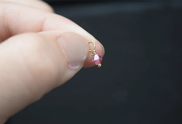 A person holding an October Birthstone 4mm Dangle in their hand.
