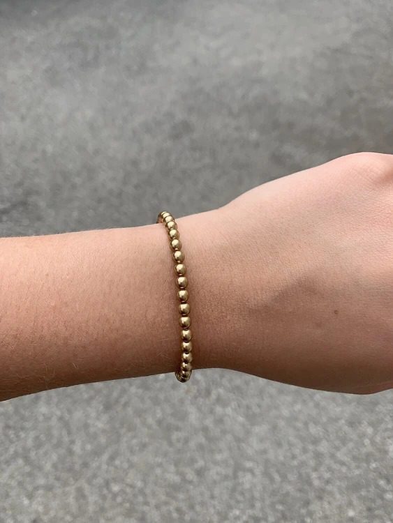 A woman wearing a Bright Gold Pearl Bracelet.