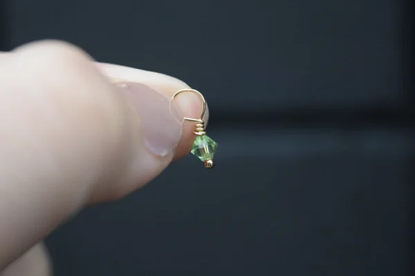 A person holding a small gold plated July Birthstone 4mm Dangle.