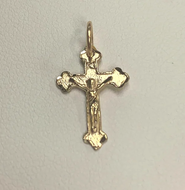 A gold crucifix pendant on a white surface