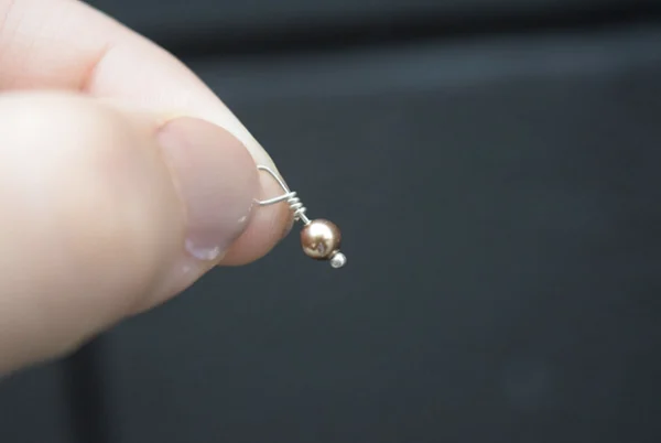 A person holding a Bright Gold Pearl 4mm Dangle.