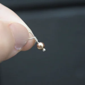 A person holding a Bright Gold Pearl 4mm Dangle.