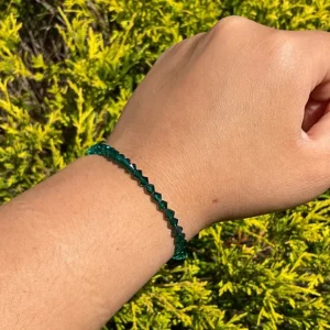 A person wearing a May Birthstone - Emerald Crystal Bracelet with emerald beads.