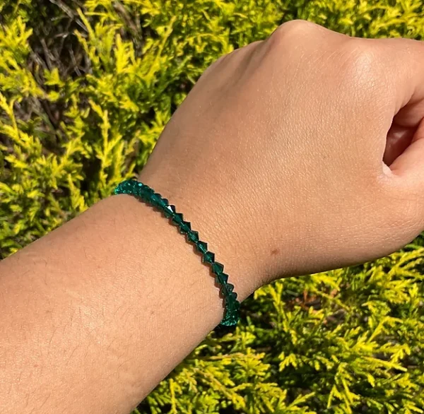A person wearing a May Birthstone - Emerald Crystal Bracelet with emerald beads.