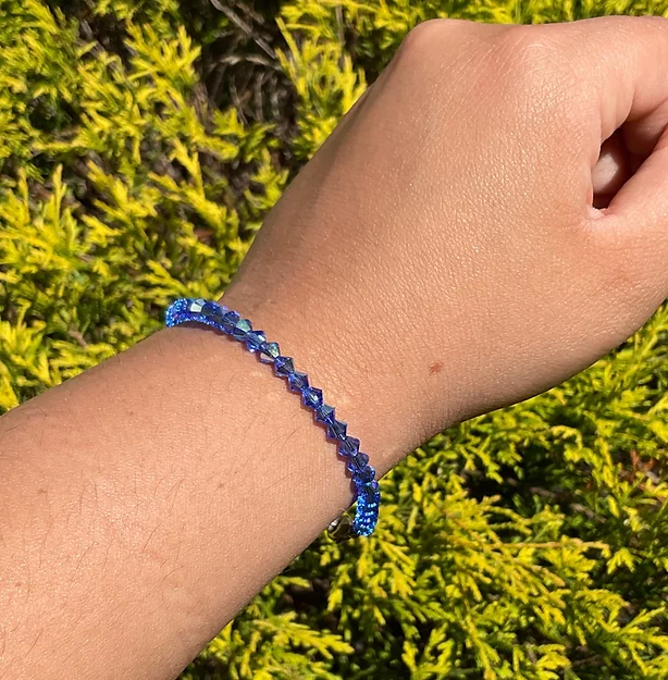 A person wearing a September Birthstone - Sapphire Crystal Bracelet.