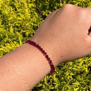 A person's hand with a January Birthstone - Garnet KIDS Crystal Bracelet.