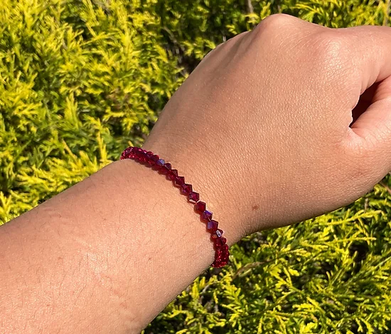 A person's hand with a January Birthstone - Garnet KIDS Crystal Bracelet.
