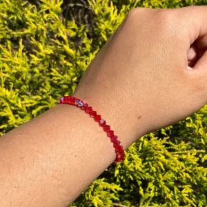 A woman's hand with a July Birthstone - Ruby KIDS Crystal Bracelet.