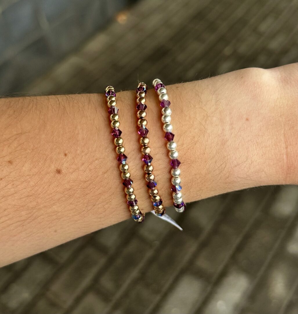 Two February Birthstone - Amethyst Crystal Stretch Bracelets on a woman's wrist.