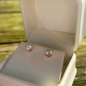 A pair of Gold Diamond Studs in a white box.