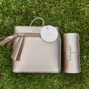 A Hollis Rose Gold Mini Makeup Bag with Mini Brush Holder with a tassel sitting on the grass.