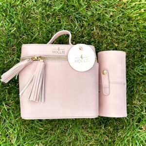 A Hollis Blush Mini Makeup Bag with Mini Brush Holder with a tassel sitting on the grass.