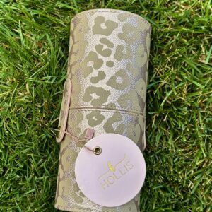 A gold and leopard print Hollis Leopard Brush Holder Makeup Travel Container laying on the grass.