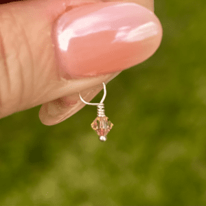 A person holding a small pink November Birthstone 4mm Dangle.