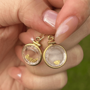 A person is holding a pair of 14K Yellow Gold Nugget Locket earrings.