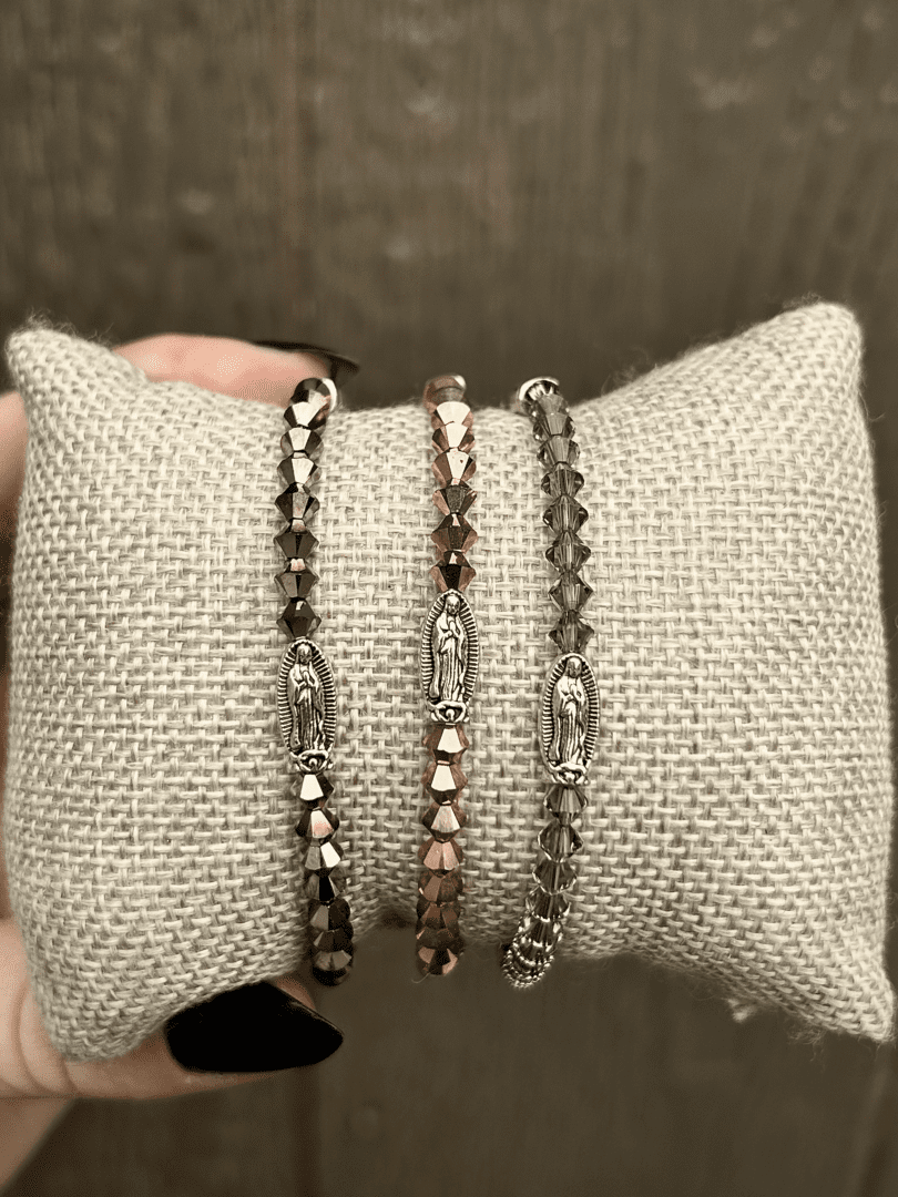 A person holding three Miraculous Bracelets on a pillow.