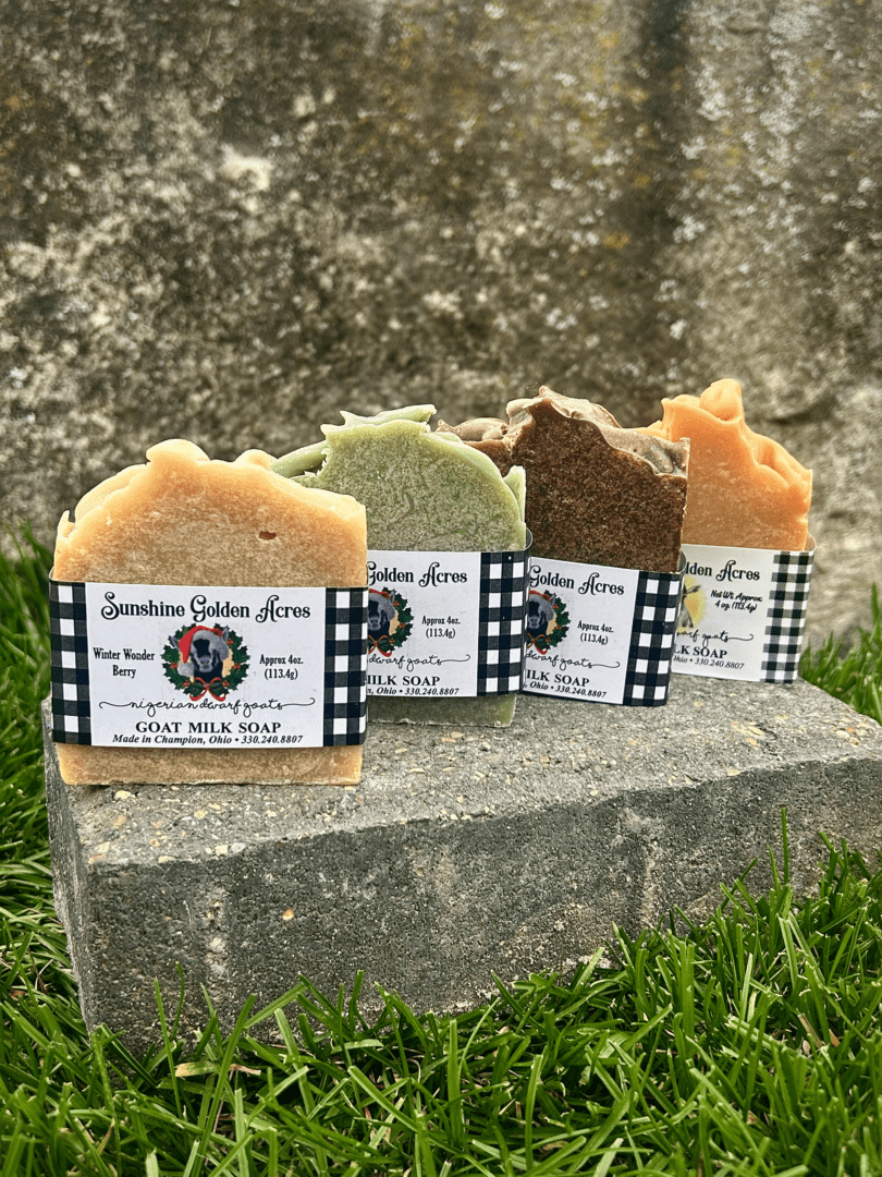 Four Sunshine Golden Acres Bar Soaps sitting on top of a block of grass.