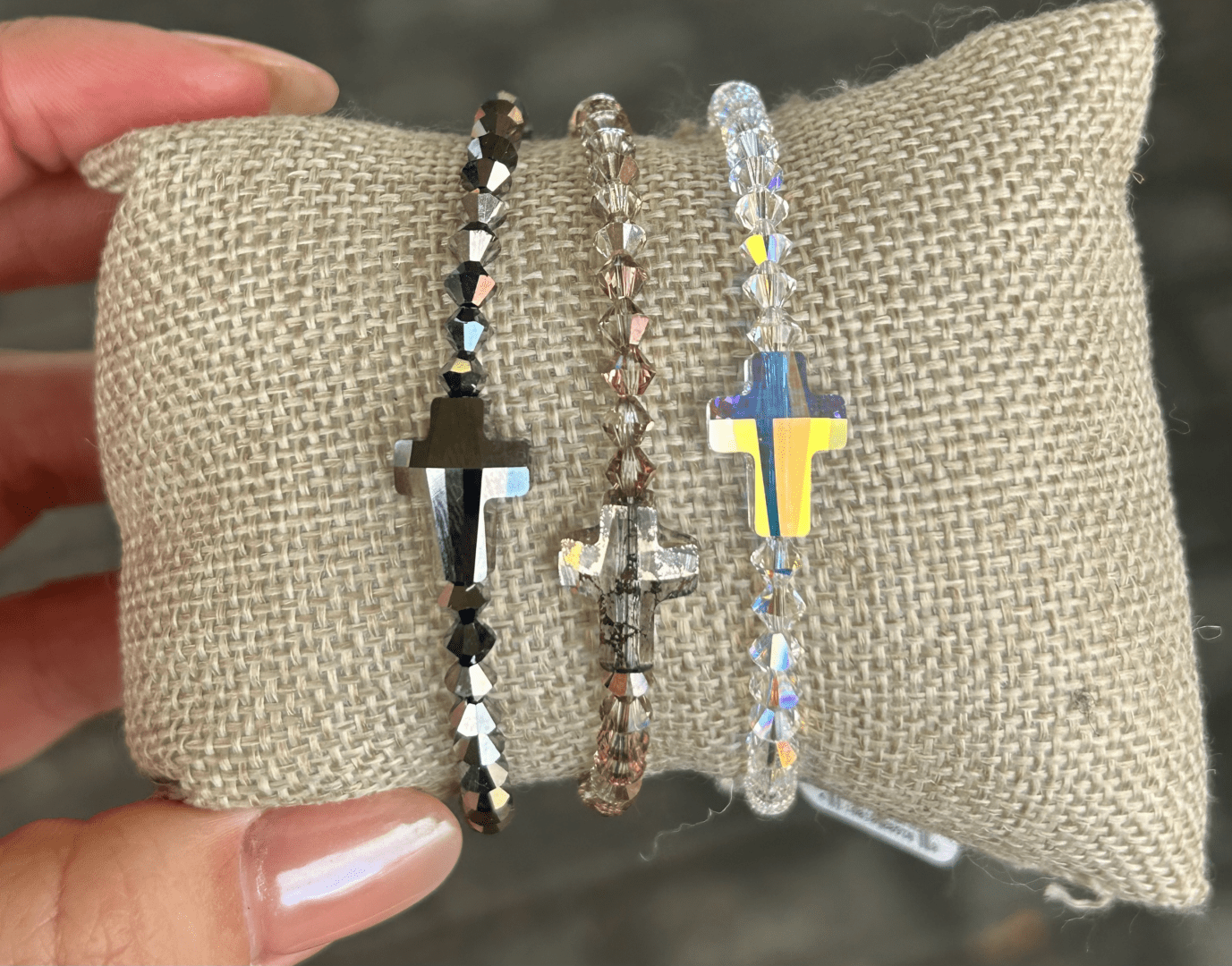 A person holding a Patina Cross Crystal Bracelet set