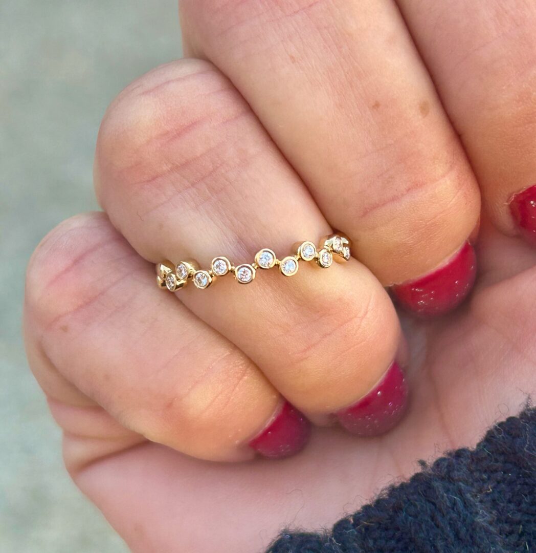 A woman's hand holding a Gold Diamond Staggered Ring.