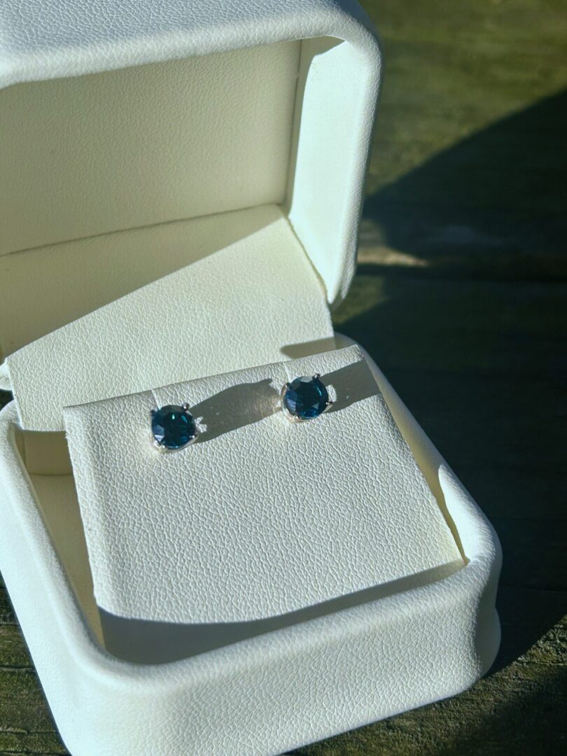 White Gold Blue Diamond stud earrings in a white box.